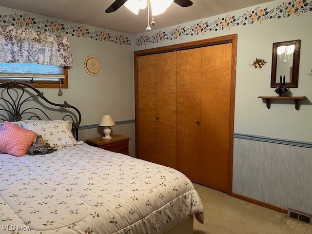 carpeted bedroom featuring ceiling fan and a closet