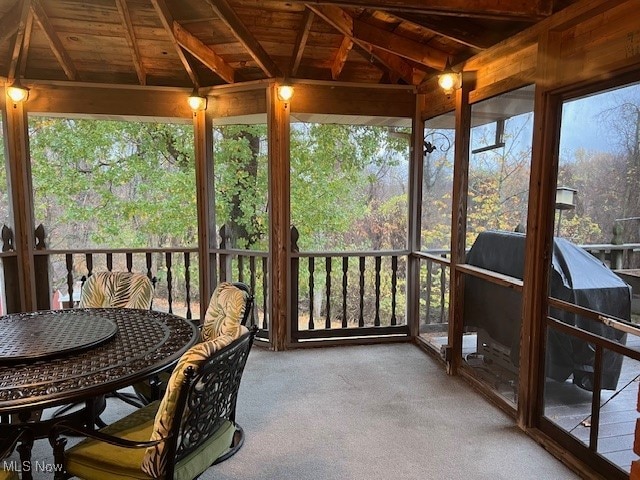 sunroom / solarium with lofted ceiling with beams, a wealth of natural light, and wooden ceiling