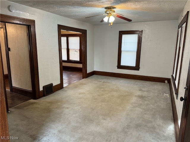 carpeted empty room with ceiling fan and a textured ceiling