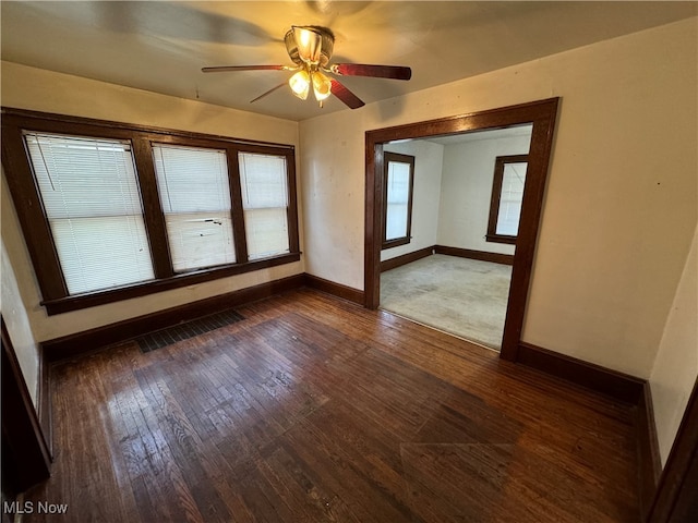 spare room with dark wood-type flooring and ceiling fan