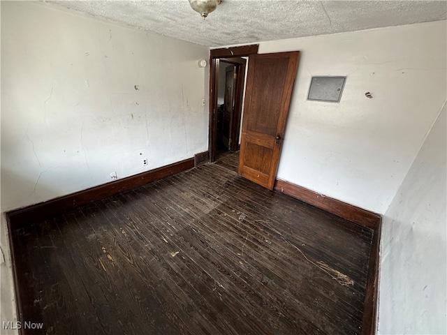 empty room featuring a textured ceiling and dark hardwood / wood-style floors