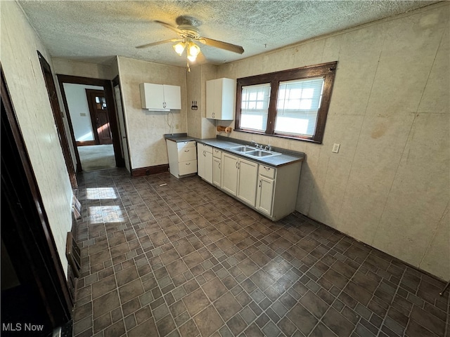 kitchen featuring a textured ceiling, sink, ceiling fan, and white cabinets