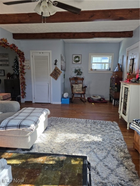 living room featuring dark wood-type flooring, ceiling fan, and beam ceiling