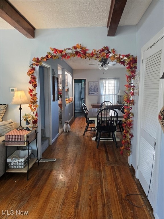 dining space featuring beam ceiling, a textured ceiling, and dark hardwood / wood-style flooring