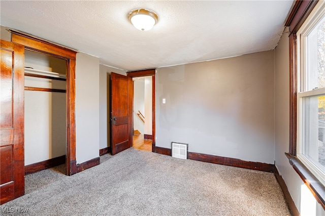 unfurnished bedroom with a closet, a textured ceiling, and light carpet