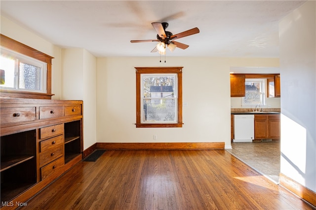 unfurnished living room featuring a wealth of natural light, ceiling fan, sink, and hardwood / wood-style flooring