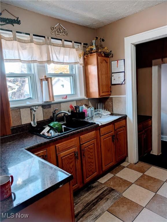 kitchen with tasteful backsplash, sink, and a textured ceiling