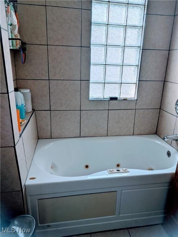 bathroom featuring tile patterned floors, a bathing tub, and tile walls