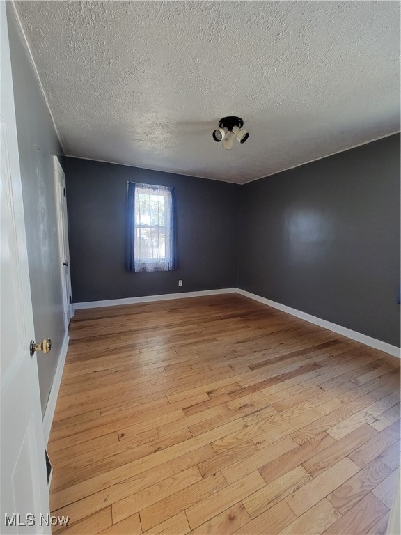 spare room featuring light hardwood / wood-style floors and a textured ceiling