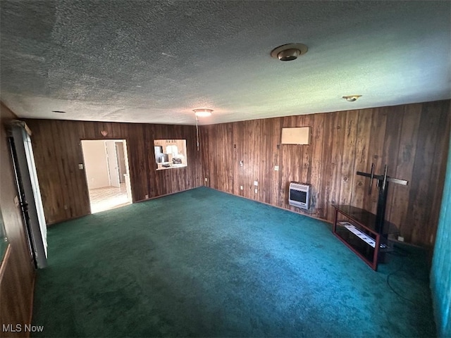 interior space featuring heating unit, wooden walls, carpet flooring, and a textured ceiling