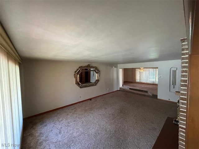 unfurnished living room with a chandelier and dark colored carpet