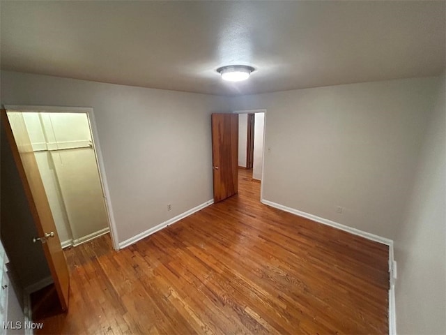 unfurnished bedroom featuring a closet, a walk in closet, and wood-type flooring