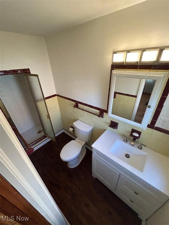 bathroom with wood-type flooring, vanity, toilet, and tile walls