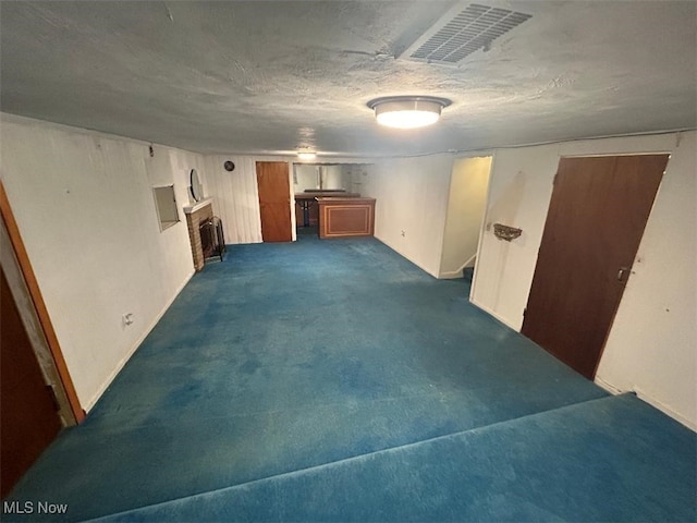 basement featuring a textured ceiling and dark carpet