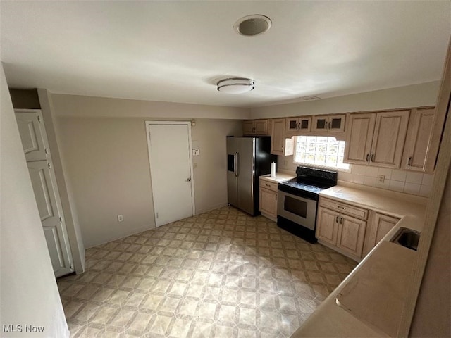 kitchen with range, sink, backsplash, light brown cabinetry, and stainless steel fridge