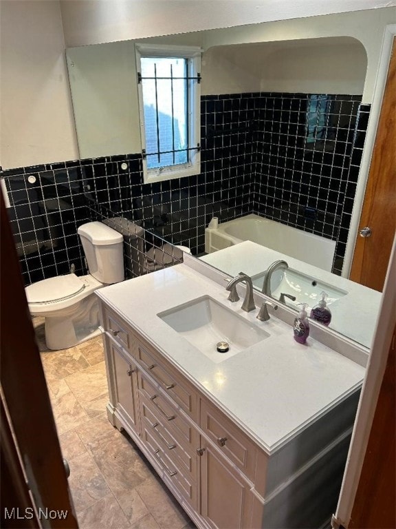 bathroom featuring toilet, vanity, and tile walls