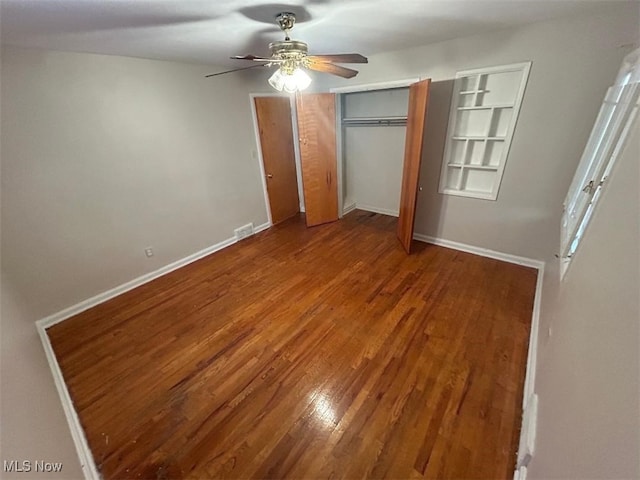 unfurnished bedroom featuring hardwood / wood-style floors, ceiling fan, and two closets