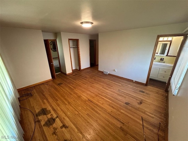 unfurnished bedroom with light wood-type flooring and ensuite bathroom