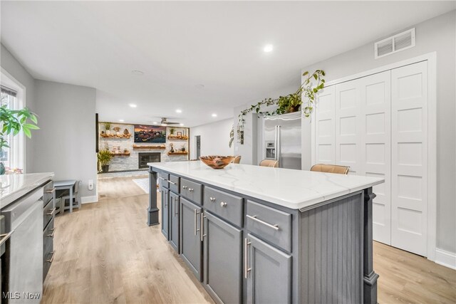 kitchen featuring gray cabinets, a center island, appliances with stainless steel finishes, and light hardwood / wood-style flooring