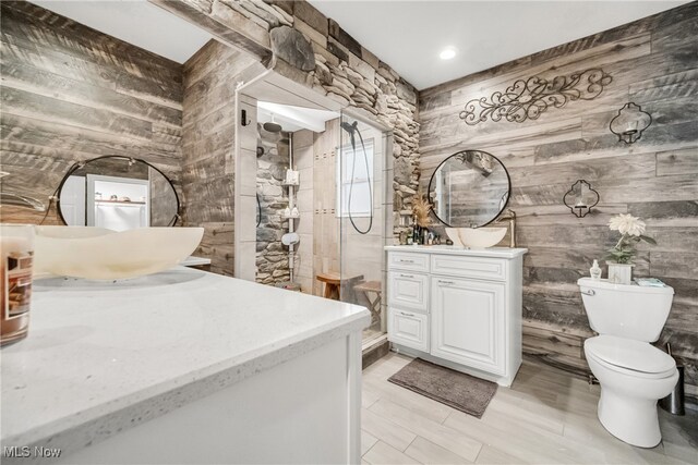 bathroom featuring wood walls, vanity, toilet, and a shower