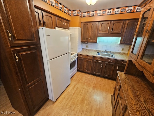 kitchen with sink, light stone counters, white appliances, light wood-type flooring, and decorative backsplash