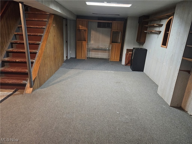 basement featuring wood walls and light carpet