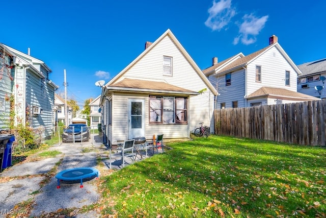 back of property with a lawn and a patio