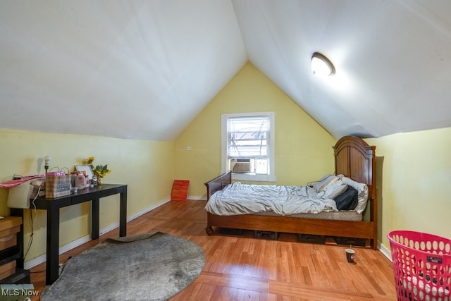 bedroom featuring hardwood / wood-style floors, lofted ceiling, and cooling unit