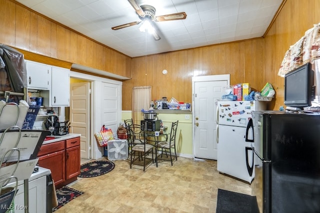 kitchen with black fridge, white refrigerator, wooden walls, and ceiling fan