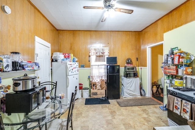 kitchen featuring black fridge, white refrigerator, wooden walls, and ceiling fan