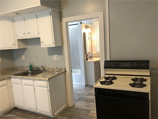 kitchen with dark hardwood / wood-style floors, white cabinetry, white gas range, and sink