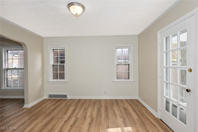 spare room with light wood-type flooring and crown molding