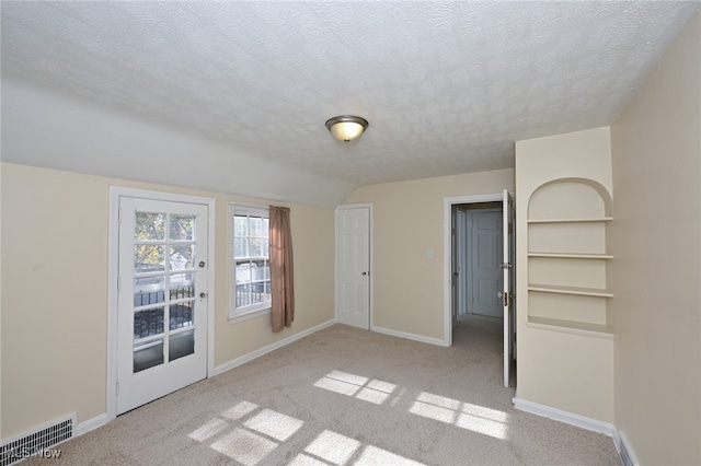 spare room with a textured ceiling and light carpet