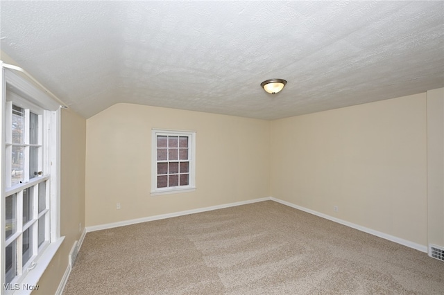 spare room with lofted ceiling, carpet floors, and a textured ceiling