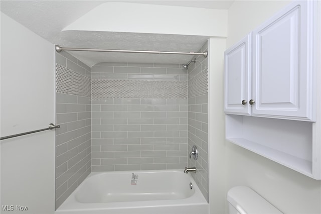 bathroom featuring a textured ceiling, toilet, and tiled shower / bath