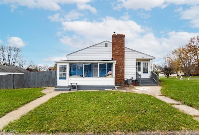 back of property featuring a lawn, a sunroom, and central air condition unit