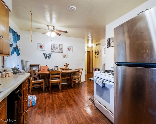 kitchen featuring white gas stove, ceiling fan, dark hardwood / wood-style floors, and stainless steel refrigerator