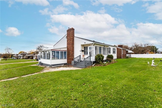 rear view of house with a sunroom and a yard