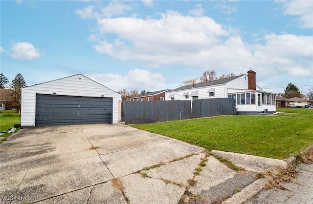 view of side of property featuring a sunroom, a garage, a yard, and an outbuilding