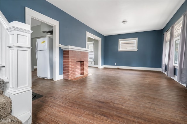 unfurnished living room with a brick fireplace and dark hardwood / wood-style flooring