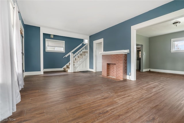 unfurnished living room with a brick fireplace and dark hardwood / wood-style flooring