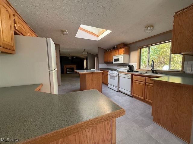 kitchen with decorative backsplash, sink, a kitchen island, vaulted ceiling with skylight, and white appliances