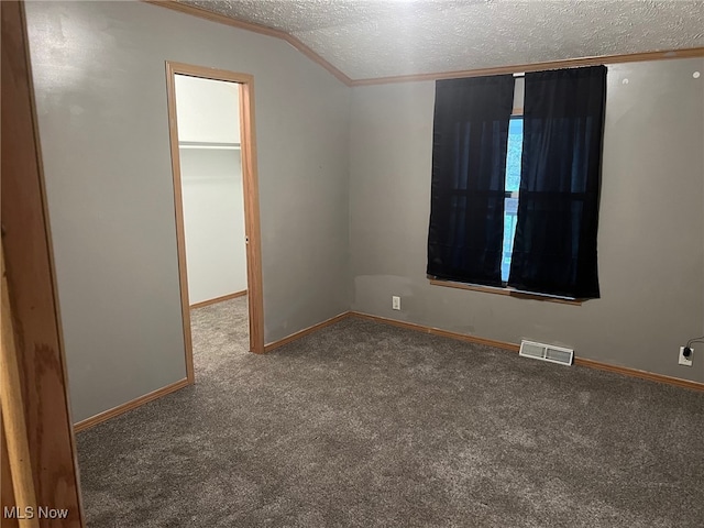 unfurnished room with carpet, a textured ceiling, and vaulted ceiling