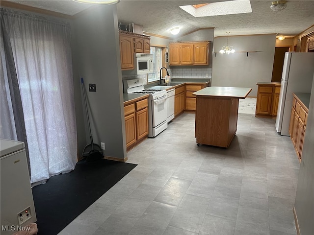 kitchen featuring sink, vaulted ceiling with skylight, a textured ceiling, white appliances, and a kitchen island