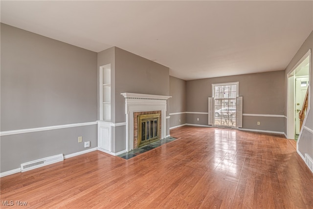 unfurnished living room with a brick fireplace and wood-type flooring