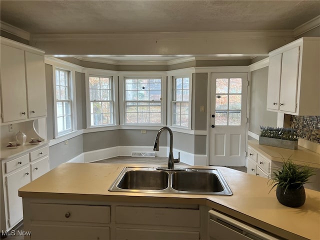 kitchen featuring sink, stainless steel dishwasher, crown molding, backsplash, and white cabinetry