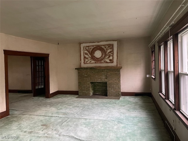 unfurnished living room featuring a brick fireplace and carpet floors