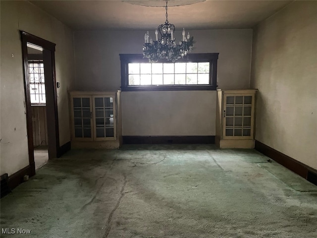 interior space with light colored carpet, plenty of natural light, and an inviting chandelier