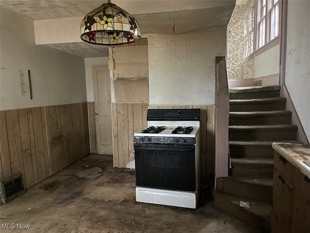 kitchen featuring wooden walls and white gas stove