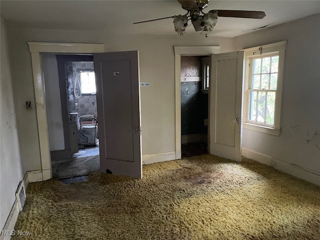 interior space featuring multiple windows, dark carpet, and ceiling fan